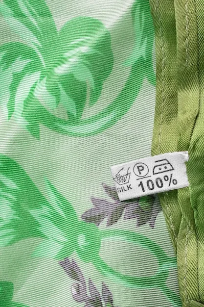 Close-up of a garment label displaying certifications such as GOTS (Global Organic Textile Standard) and Fair Trade, along with detailed information about the fabric composition (e.g., 100% organic cotton) and origin. The label is attached to a simple, well-made article of clothing.