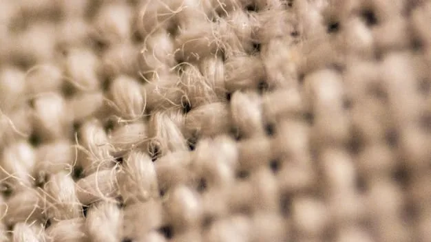 A close-up shot of linen fabric showing its texture and weave. Focus on the natural fibers and the way light passes through the material.