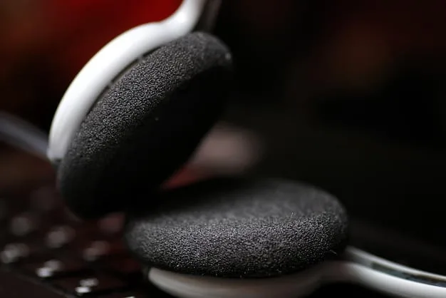 Close-up of the earcup of a noise-canceling headphone, highlighting the intricate details of the speaker grill and cushioning. The background is blurred to emphasize the headphone.