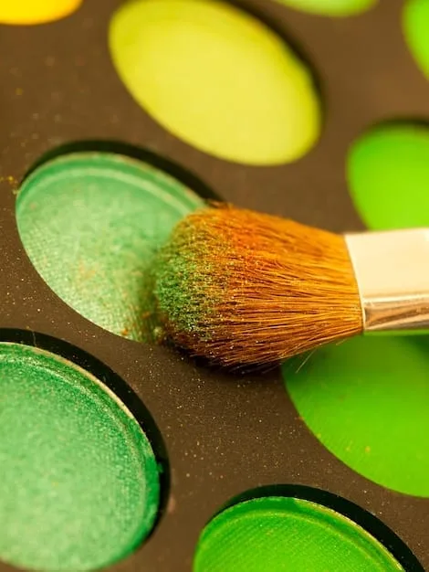 A close-up of a paint swatch palette showing various shades of green, ranging from light sage to deep forest green. The texture of the paint is visible, and natural light highlights the subtle variations in color.