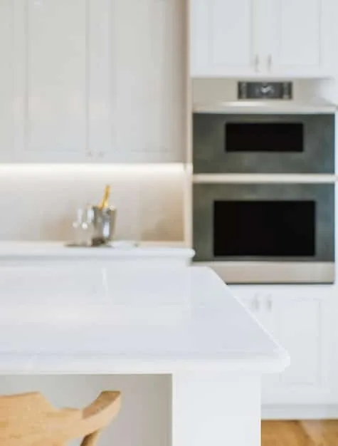 A brightly lit kitchen with freshly painted cabinets, stainless steel appliances, and a clean countertop with minimal decor.
