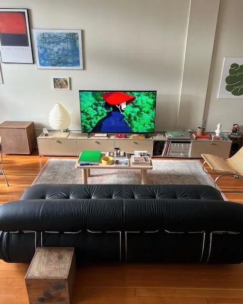 A comfortable living room with a large smart TV mounted on the wall displaying vibrant content, subtle smart light strips illuminating the back of the TV, and smart speakers discretely placed, creating an inviting entertainment space.